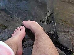 I grandi e pelosi piedi di Mika godono del gioco a piedi nudi nell'acqua